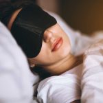 Woman sleeping with eye mask on bed