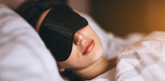 Woman sleeping with eye mask on bed