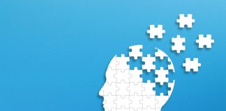 Silhouette head made of puzzle pieces on blue background