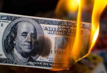 Hundred dollar bill burning with orange flames