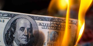 Hundred dollar bill burning with orange flames