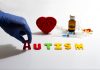 Gloved hand placing autism letters near medical items