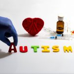 Gloved hand placing autism letters near medical items