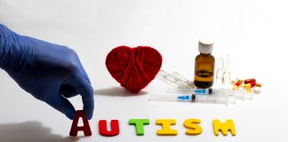 Gloved hand placing autism letters near medical items