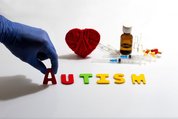 Gloved hand placing autism letters near medical items