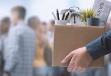 Person holding box with office items and newspaper