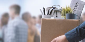 Person holding box with office items and newspaper