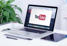 Laptop displaying YouTube, with coffee and stationery nearby