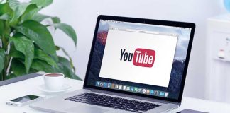 Laptop displaying YouTube, with coffee and stationery nearby