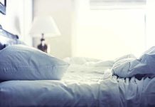 A cozy unmade bed with soft pillows and bedding in a well lit room