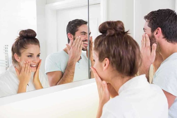 shutterstock_232063255.jpg A couple smiling at their reflections in a bathroom mirror while applying skincare products