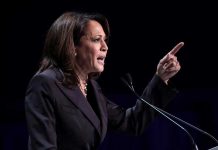 Person speaking at podium with raised finger