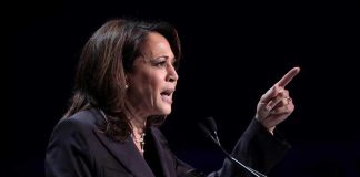 Person speaking at podium with raised finger