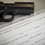 A handgun placed on top of a concealed carry license application form