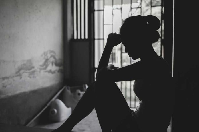 2321080413 Silhouetted person sitting by a window, deep in thought.