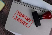 Inflation SPIKE COSTS U.S. – Surges Ahead Notebook with Import Tariff stamp and rubber stamper.