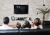 A family of four watching television together in a cozy living room