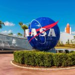 Debris Strike TRAPS Astronauts Above Earth NASA logo sculpture with spaceship and palm trees.
