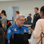 $10,000 Paydays Stun TSA Veterans TSA agent checks passengers documents at airport security.