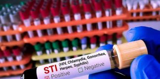Millions at Risk – Aids Cut Ignites NEW Epidemic Fears Gloved hand holding STI test tube labeled Negative.