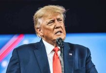 Man in suit speaking at a microphone.