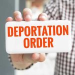 Hand holding sign with Deportation Order text.