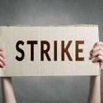 Travel Chaos Looms—Unions Tease Brutal STRIKE Two hands holding a cardboard sign saying STRIKE.