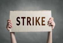 Travel Chaos Looms—Unions Tease Brutal STRIKE Two hands holding a cardboard sign saying STRIKE.