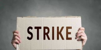 Two hands holding a cardboard sign saying STRIKE.