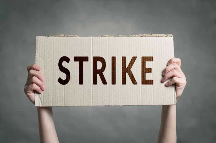 Two hands holding a cardboard sign saying STRIKE.