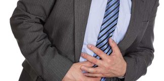 Businessman in a suit holding his stomach appearing to be in discomfort