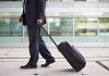 Airport Lounge PANIC—Tiny Gadget Ignites Chaos A businessman in a suit walking with a suitcase at an airport