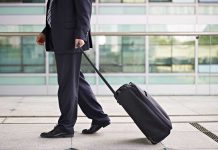 A businessman in a suit walking with a suitcase at an airport