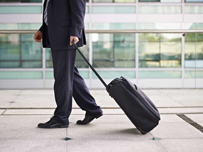 shutterstock_218424268.jpg A businessman in a suit walking with a suitcase at an airport