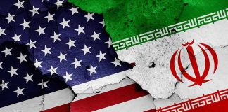 Iran President Declares TOTAL WAR on America Cracked American and Iranian flags on a wall.
