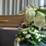 White roses in front of a casket.