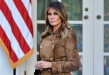 SHOCKING: Melania Launches Studio – Documentary Drops Soon Woman in brown coat beside American flag.