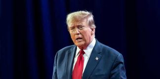 Ilhan Omar NAILS Trump – Sends Blistering Response to Attacks Man in suit with red tie speaking on stage.