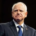 Governor’s Home Targeted: Attack Sparks Outrage Man in suit with a U.S. flag pin.