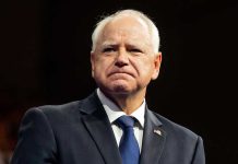 Governor’s Home Targeted: Attack Sparks Outrage Man in suit with a U.S. flag pin.