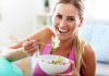 Feel Your Best In 2026: 10 Essential Winter Well-Being Trends Woman smiling and eating a salad bowl.