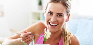 Woman smiling and eating a salad bowl.
