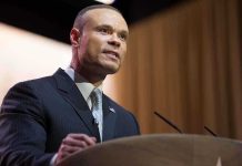 Bongino’s FBI Polygraph Scandal: What’s Really Happening? A man in a suit speaking at a podium during a conference