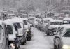 Traffic jam with cars covered in heavy snow during a snowstorm