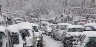 Traffic jam with cars covered in heavy snow during a snowstorm