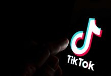 Finger pointing at TikTok logo on a screen.