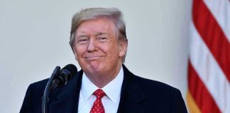 Trump SLASHES Childhood Vaccines — Medical Groups FURIOUS Man in suit and tie speaking at podium.