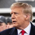 Trump THREATENS Countries Opposing His Effort to Control Greenland Man in suit and red tie speaking outside.