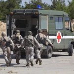 Soldiers running towards a medical vehicle during a military operation