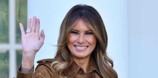 Box Office Shock: “Melania” STUNS! Person smiling and waving wearing a brown coat